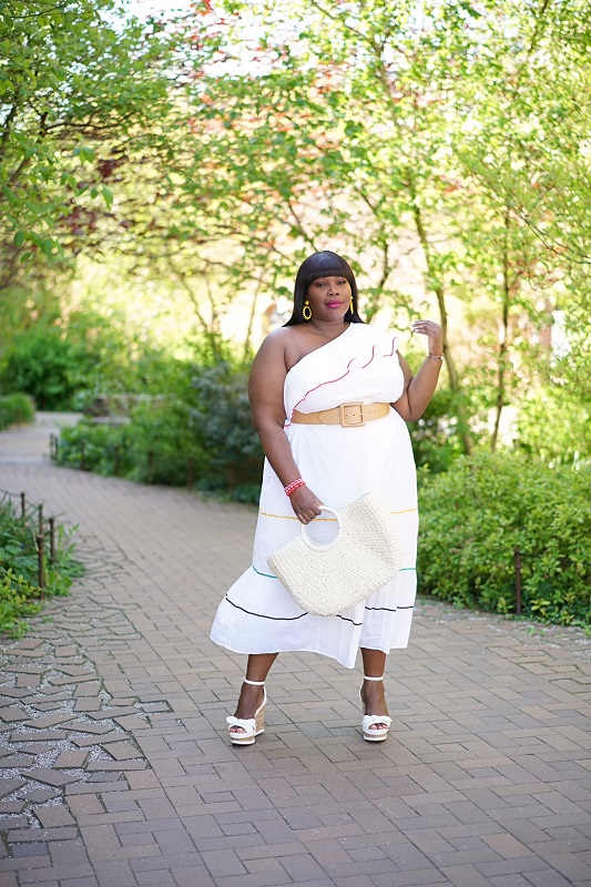 Lane Bryant spring dresses. Chic Style Edit in a white one shoulder ruffled hem dress with wedges and a straw bag